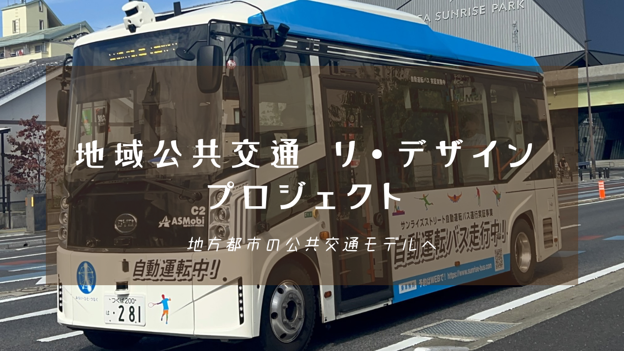 街中を走行する「自動運転中!」と書かれた白と青の小型バスを背景に、「地域公共交通 リ・デザイン プロジェクト 地方都市の公共交通モデルへ」という白い文字が中央に配置された写真