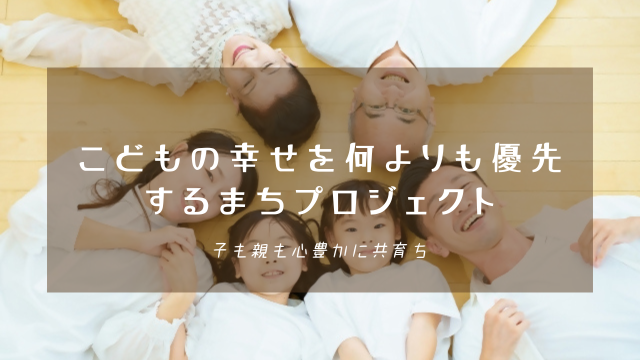 明るい部屋の床に頭を寄せ合って円の形に寝転び、笑顔を見せる三世代の家族を背景に、「こどもの幸せを何よりも優先するまちプロジェクト 子も親も心豊かに共育ち」という白い文字が中央に配置された写真