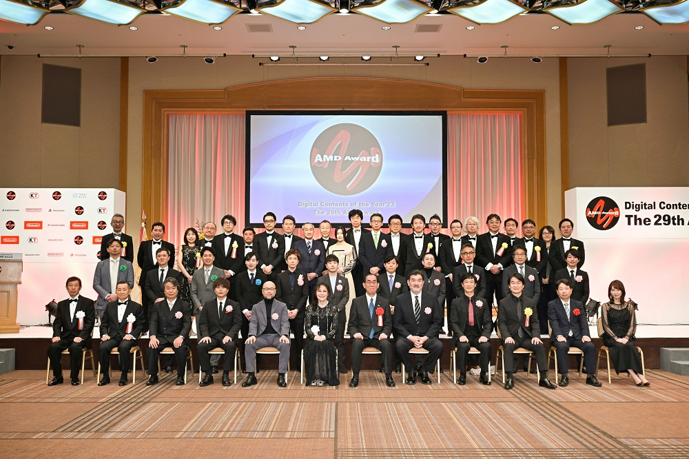 AMDアワードのロゴが映る大きなスクリーンを背に、正装した大勢の男女が一堂に会し、晴れやかな表情で記念撮影に臨んでいる第29回デジタル・コンテンツ・オブ・ジ・イヤーの授賞式会場の写真