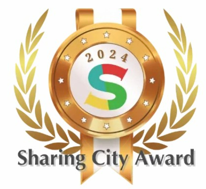 金の月桂樹の枝に囲まれたメダルの中央に2024の数字とカラフルなS字ロゴが描かれた、Sharing City Awardロゴマーク