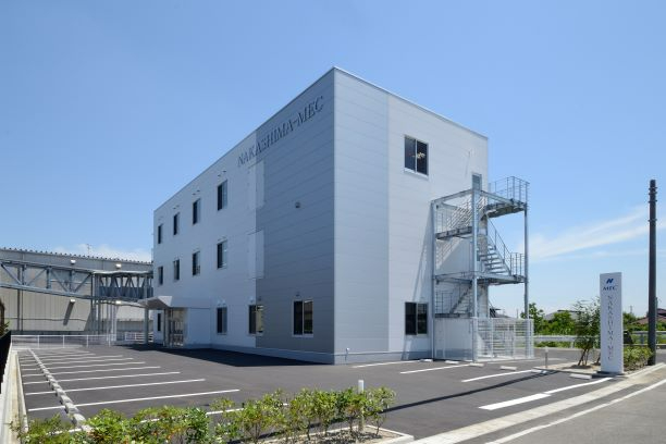 「NAKASHIMA-MEC」のロゴが壁面にある白とグレーの3階建てオフィスビルで、建物の横には屋外非常階段が設置され、手前には白線が引かれた広いアスファルトの駐車場が広がる中島製作所の外観写真