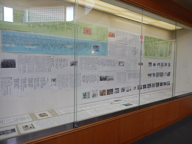 ガラス張りの展示ケース内に、当時の軍歌や流行歌の歌詞、旭日旗のイラスト、関連するエピソードや写真が記された多数のパネルが壁一面に整然と掲示されている写真