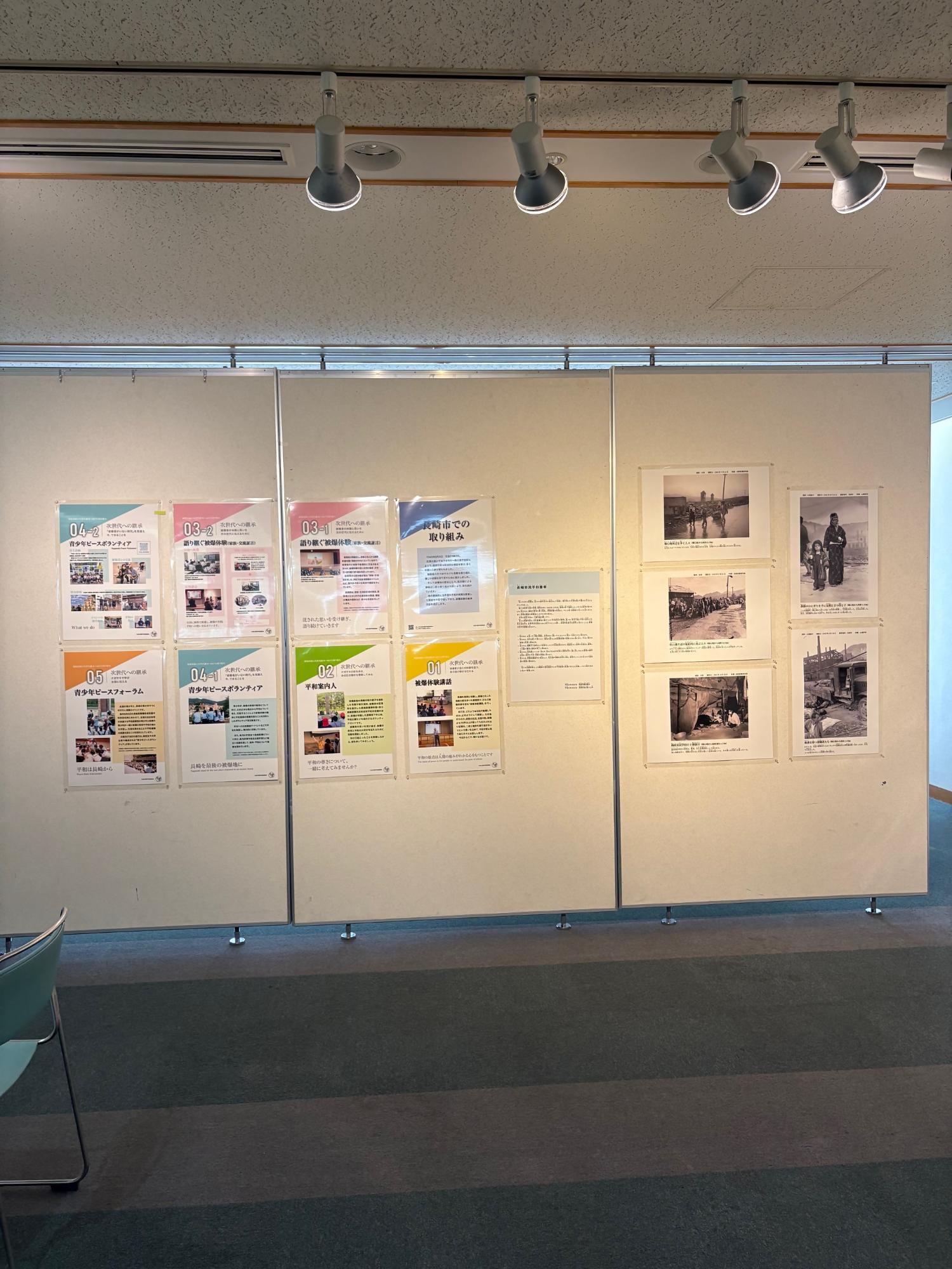 明るい展示室の白い壁面に、「長崎市での取り組み」を紹介する色鮮やかなパネルや当時の市民の暮らしを捉えたモノクロ写真が整然と掲示された展示コーナーの写真