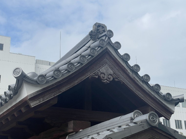 伝統的な和風建築の大屋根を近距離から見上げ、丸瓦の連なりと精巧な木彫装飾が際立ち重厚な意匠が映える様子を捉えた写真