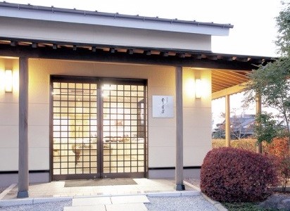 格子状の引き戸がある和風建築の入り口と、その脇に白い看板が掲げられ、手前には剪定された丸い植栽と砂利敷きの通路が広がる三福海苔の店舗正面の写真(のり道楽/三福海苔株式会社のサイトへリンク)