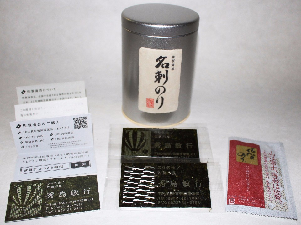 「名刺のり」と書かれた和紙ラベル付きの銀色の茶筒を中心に、佐賀市長・秀島敏行氏の名が刻まれた海苔製の名刺や、佐賀海苔の解説カード、購入案内、さらに赤いパッケージの乾燥剤が白い背景の上に並べられた特産品を紹介する写真