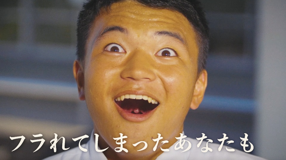 目を見開き驚いたような表情で口を大きく開けて笑う男性の顔のアップに、「フラれてしまったあなたも」という白い文字が表示されたスクリーンショット画像