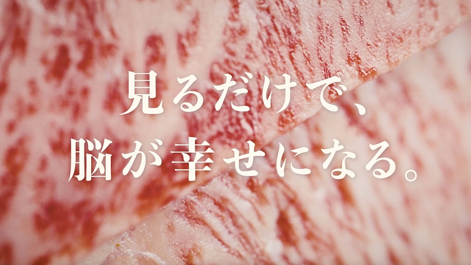 きめ細やかなサシが入った鮮やかな赤身肉の断面を背景に、中央に大きく配置されたが表示された「見るだけで、脳が幸せになる。」という白いキャッチコピーが表示されたスクリーンショット画像