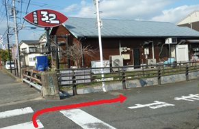 澄み渡る青空の下、「本格焼肉 3-2」と記された赤い楕円形の看板が立つ店舗の角から、手前の横断歩道を渡って右方向の道へと進むルートを、赤い矢印で分かりやすく示した道案内の写真