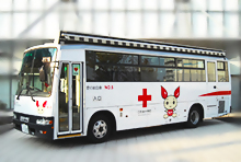 車体に赤十字のマークとキャラクターけんけつちゃんが描かれた献血バスの写真