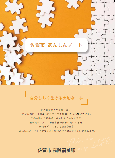 オレンジ色の背景に白いジグソーパズルのピースが散りばめられたデザインが施された、佐賀市あんしんノート表紙画像