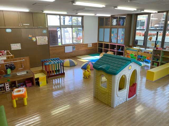 明るい室内に家形玩具やミニキッチン、マットや棚付き遊具が整然と配置された広い遊び場の写真