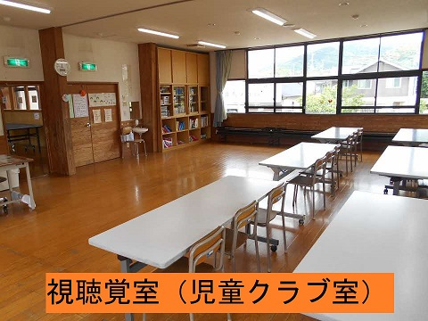 大きな窓のある明るい視聴覚室に白い机と椅子が整然と並び、壁際に本棚や収納が配置された写真