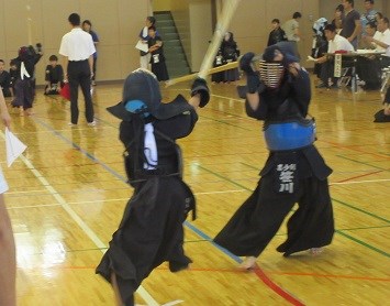 体育館で防具を着けた二人の剣道選手が素早い動きで竹刀を激しく振り交わし迫力ある攻防を繰り広げる写真