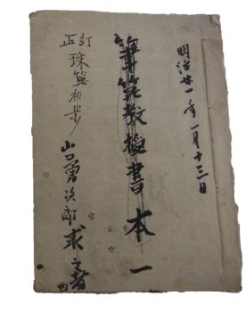 「筆算教授書本一」という題名を中心に、右側に日付、左側に「訂正珠算初歩」といった文字が墨書きされた経年による色あせや端の傷みが見られる和紙の教科書写真