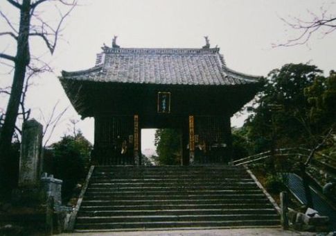 石段の先に佇む重厚な瓦屋根の山門であり、中央に掲げられた扁額や左右の格子戸が寺院の歴史と格調を感じさせ、周囲の木々と調和しながら静謐な境内への入り口を形成している仁王門の写真