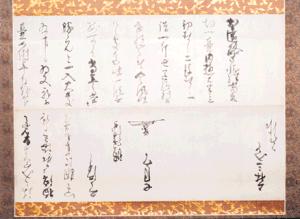 上下に金糸の装飾が施された華やかな裂地で表装され、白地の紙に黒々とした墨で流麗な崩し字の文章と署名、そして中央下部には特徴的な花押が記された上林家文書の写真