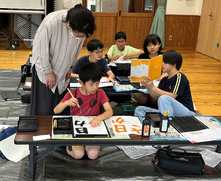 子ども達が書道の先生から書道の指導を受けている