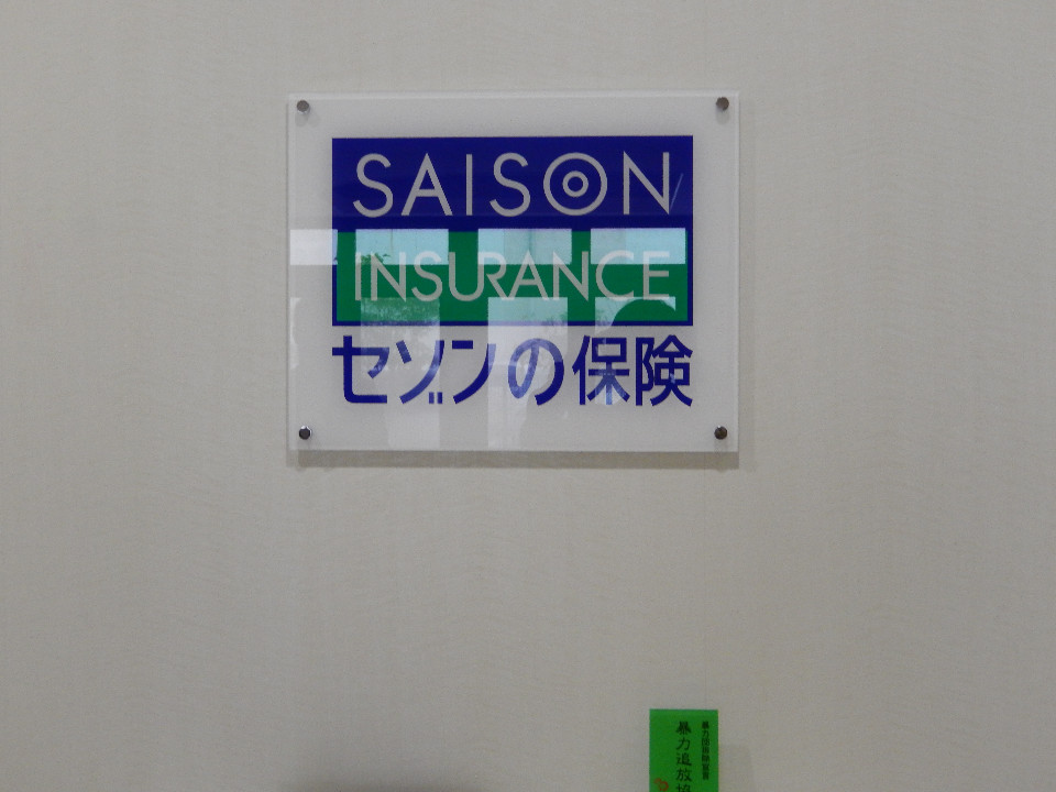 透明なアクリル板に、「SAISON INSURANCE」「セゾンの保険」と記された、ロゴ写真