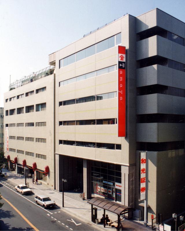 道路沿いに建つ多階建ての大きなビル壁面に、赤地に白文字で「Tamaya」と書かれた長い縦看板が設置されている佐賀玉屋の外観写真
