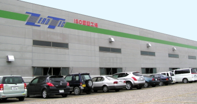 「LEADTEC ISO認証工場」という看板とロゴが壁面に掲げられたグレーの大きな工場の聖徳ゼロテック株式会社の外観写真