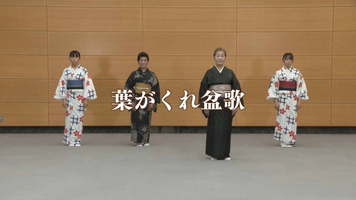 中央には大きく「葉がくれ盆歌」という白い文字が重なるように配置され、格子模様の壁を背景に、色とりどりの着物や浴衣を身にまとった4人の女性が等間隔に並んでいる「葉がくれ盆歌」の踊り講習映像が表示された画面キャプチャ（ 佐賀城下栄の国まつり 葉がくれ盆歌 講習ビデオ（YouTube））
