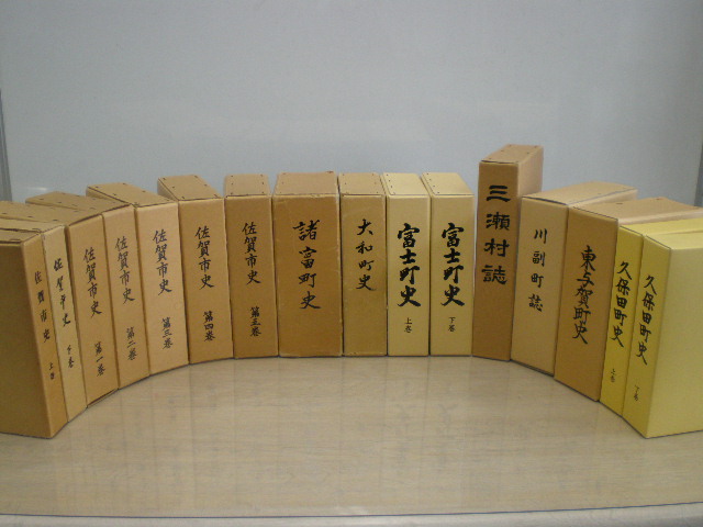 薄茶色の和装本が半円形に並び、背表紙に佐賀県史や宮之城町史などの地方史料のタイトルが縦書きで記されている写真
