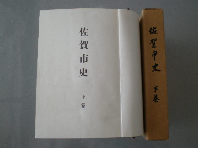 薄茶色のカバーに佐賀市史下巻と縦書きで印刷された函と、開かれた本文ページに佐賀市史下巻の表紙が見える佐賀市史(旧版):下巻の写真