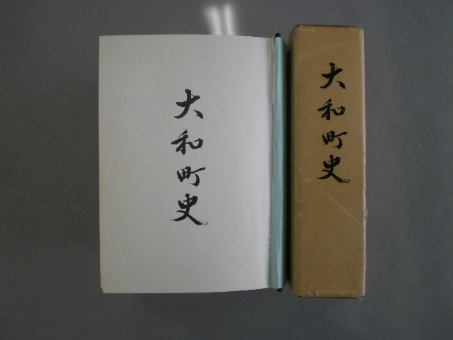 茶色の函に大和町史と縦書きされた背表紙と、開かれた白い表紙ページに大和町史の文字が見える大和町史の写真