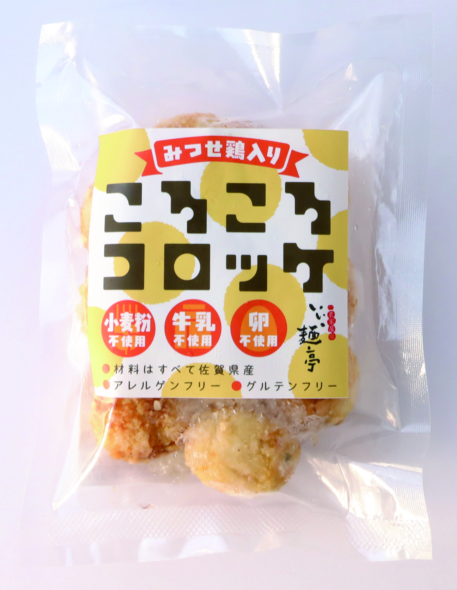 黄色の水玉模様と「みつせ鶏入り こりこりコロッケ」という大きな文字がデザインされたラベルが貼られ、小麦粉・牛乳・卵不使用といったアレルゲン情報のアイコンが並ぶ、透明な袋に入った冷凍コロッケのパッケージ写真
