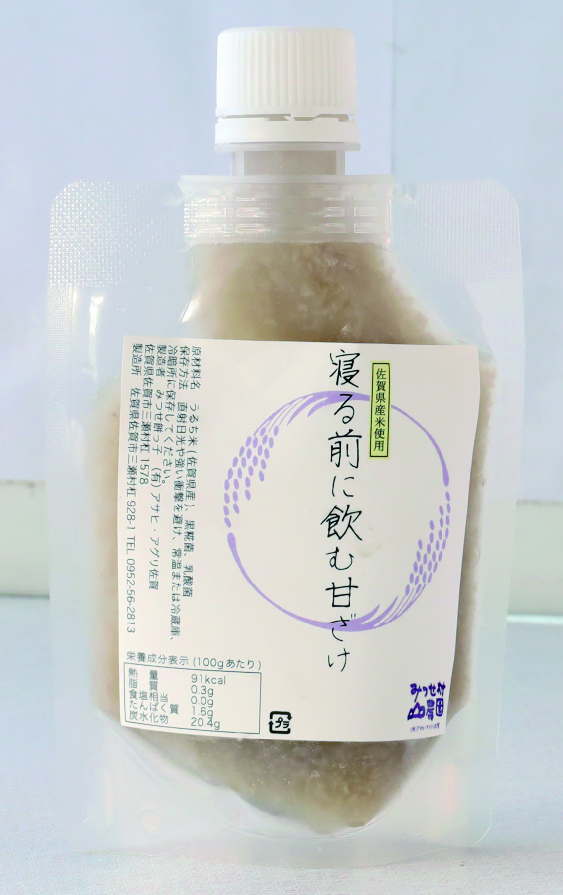 稲穂の輪のイラストと「寝る前に飲む甘ざけ」という文字がデザインされたラベルが貼られた、白濁した甘酒が入ったキャップ付きパウチ容器の商品の写真