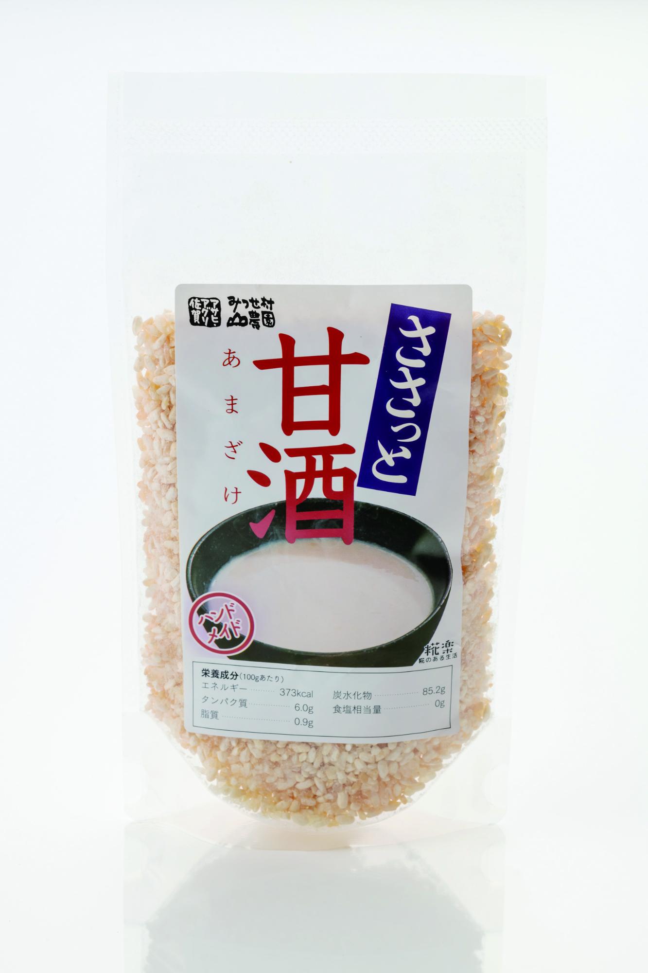 大きな赤い「甘酒」の文字と「ささっと」という青い帯のデザインが印象的なラベルが貼られた、乾燥した米麹がたっぷりと入った透明な自立型パウチ容器の商品の写真