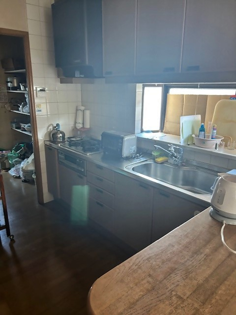 調理器具や家電が並ぶキッチンで流し台と作業台が明るい窓辺に配置された室内の写真
