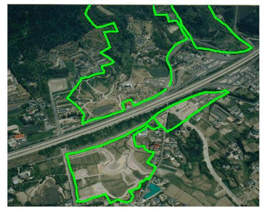 高速道路が中央を横断する丘陵地や集落の航空写真において、金立公園のエリアを示すような複雑な形状の緑色の太い枠線が、北側の山林に近いエリアから南側の平地にかけて複数箇所に描かれている写真