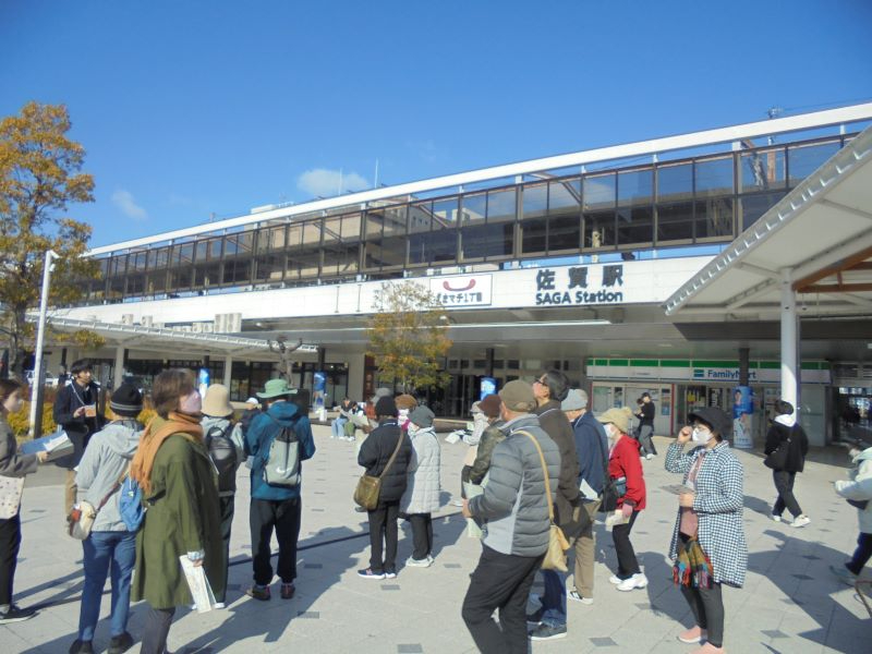 青空の下の佐賀駅前広場で多くの来訪者が建物を背に集まり談笑しながら行き交う様子を捉えた写真