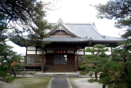 日本の伝統的な木造建築である寺院が正面から撮影され、瓦屋根と彫刻装飾が特徴的で、周囲には松の木が植えられた庭が広がる平安山 龍泰禅寺の写真