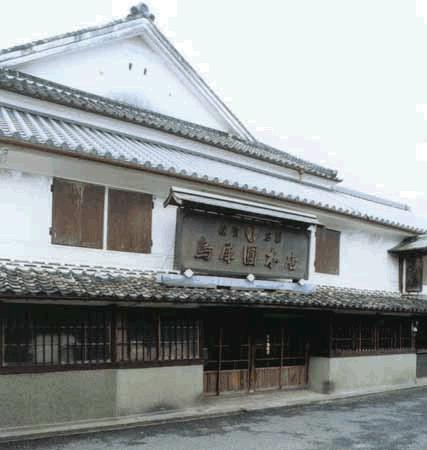 白壁と瓦屋根が特徴的な日本の伝統的建築で、正面に大きな木製看板が掲げられ、格子窓が並ぶ歴史的な商家風の野中ウサイエンの外観写真