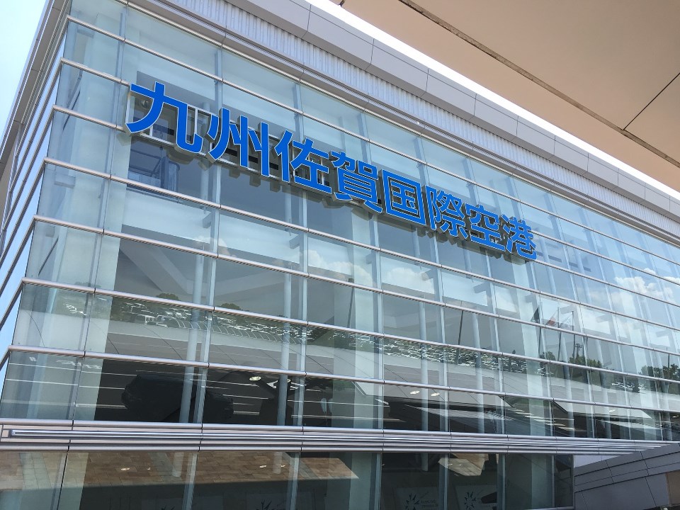 ガラス張りの外観に「九州佐賀国際空港」の青い文字が大きく掲げられた建物を見上げる構図の写真