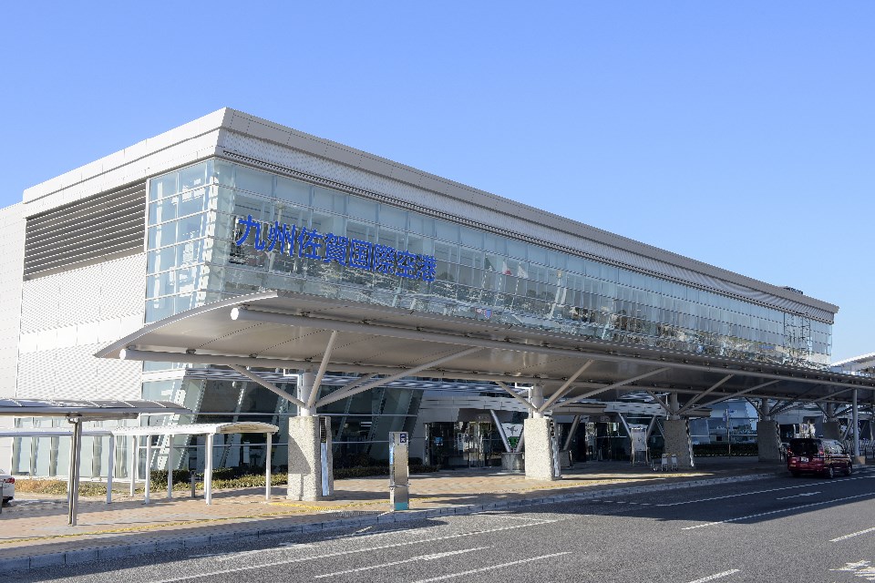 ガラス張りの外観に「九州佐賀国際空港」の文字が掲げられた空港ターミナルを道路越しに捉えた写真