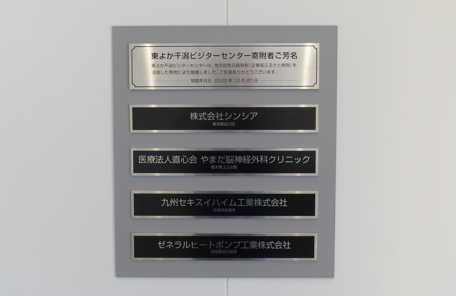 よか干潟ビジターセンター寄附者ご芳名と記された金属プレートと4社の企業名が地名と共に黒地のプレートに刻まれた2020年10月20日開館時の寄附者銘板の写真
