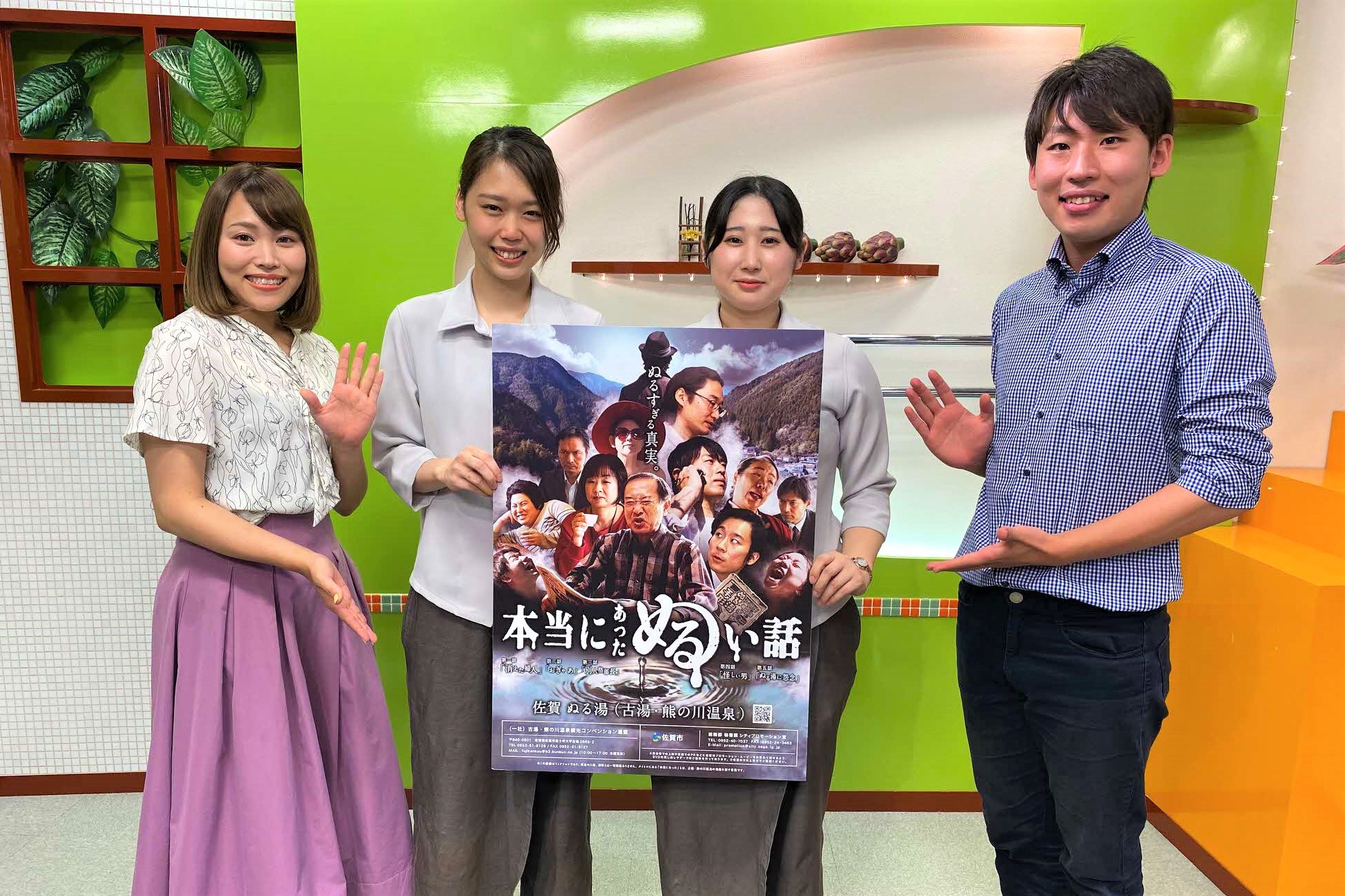 「本当にあったぬるい話」というポスターを中央に掲げた男女4人が、緑を基調としたスタジオセットで笑顔を浮かべながらポスターを指差し、佐賀の温泉イベントを紹介している和やかな雰囲気の広報用写真