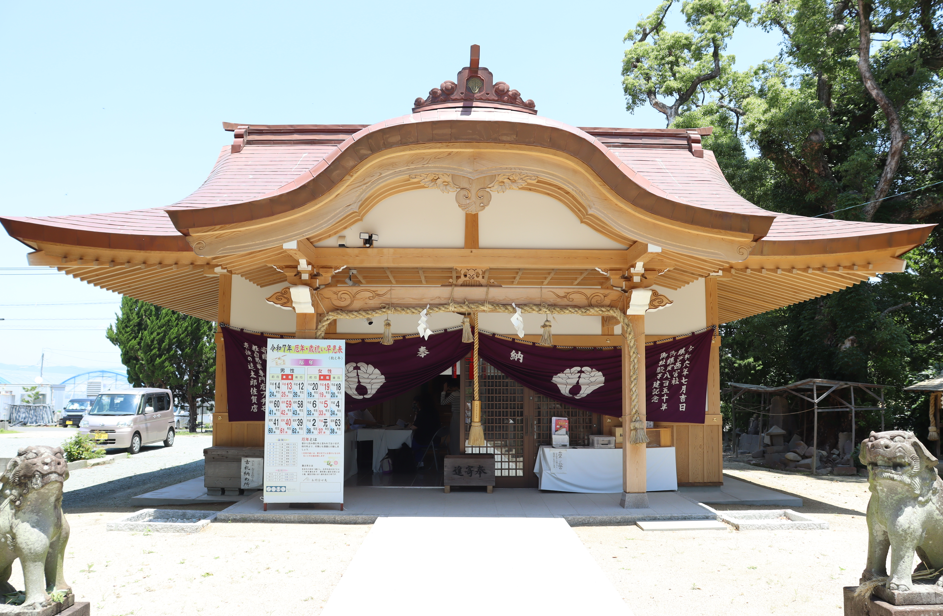 新しく美しい木造建築の拝殿が建っており、正面には注連縄が飾られ、紫色の幕の間から内部の様子が伺えるほか、手前左右には一対の狛犬が鎮座して静かに境内を見守ってい神社の写真る