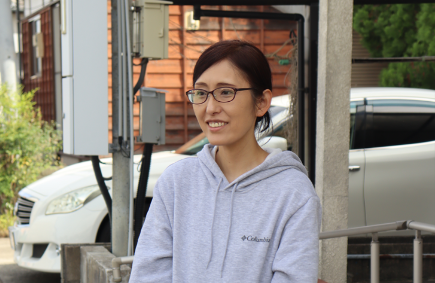 グレーのパーカーを着用し、眼鏡をかけた納富里美さんが話をしている様子を斜めから撮影した写真