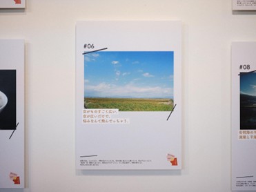 抜けるような青空と広大な田園風景を捉えた写真が中央に配置され、その下に「空がものすごく広い。空が広いだけで、悩みなんて飛んじゃう。」というキャッチコピーが添えられた、壁面に展示されている「#06」のパネルの写真