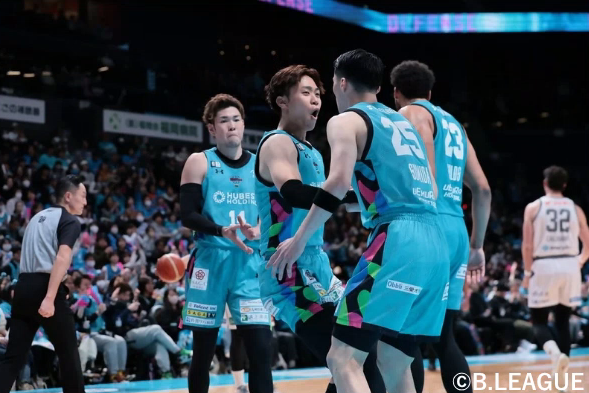 水色のユニフォームを纏った佐賀バルーナーズの井上選手とチームメイトたちがコート上で顔を輝かせ、互いに声を掛け合っている試合中の写真