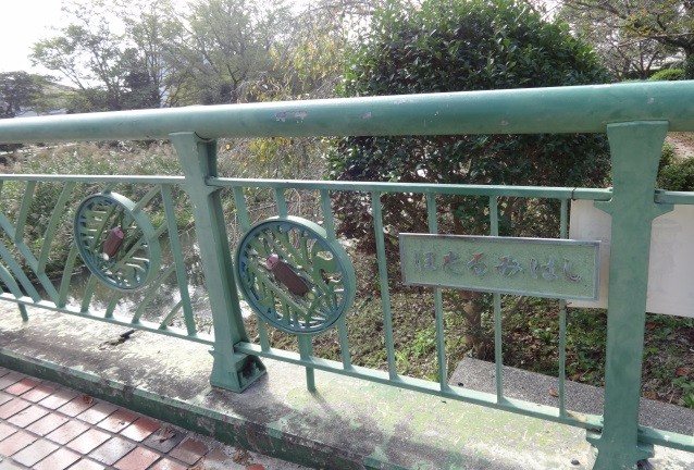 緑色の橋の欄干に丸い装飾と銀色の名称板が並ぶほたるみばしの写真