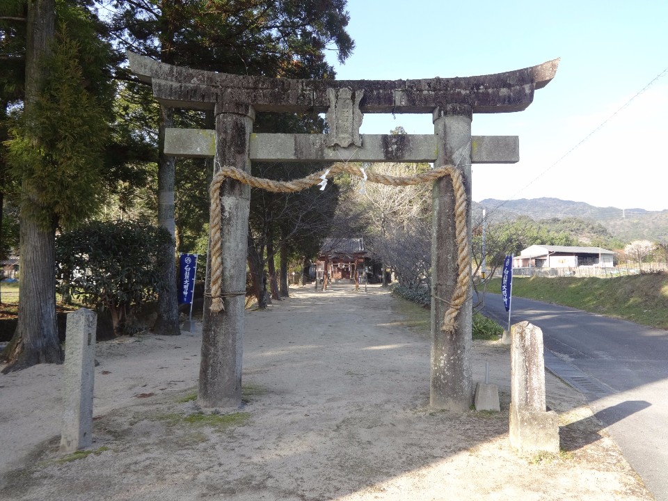 晴天の下、山々を遠景に望むのどかな風景の中、立派な注連縄が飾られた石造りの鳥居の奥へと続く砂利の参道と、その先に佇む社殿の様子を捉えた、佐賀市のウォーキングコース沿いにある白髭神社の写真