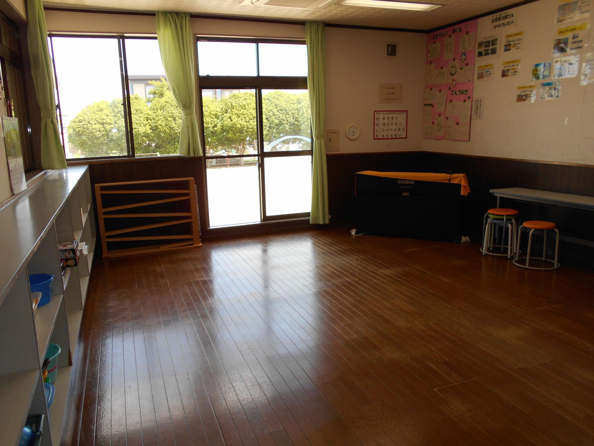 大きな窓から光が差し込む明るい室内に木床や棚と机が整然と並び、壁面に掲示物が貼られたセンター室の様子を写した写真