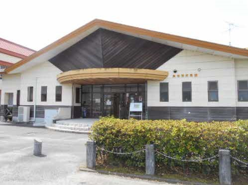 木目調の大きな三角屋根とガラス扉を備えた東与賀児童館の正面外観が植え込み越しに広がる写真