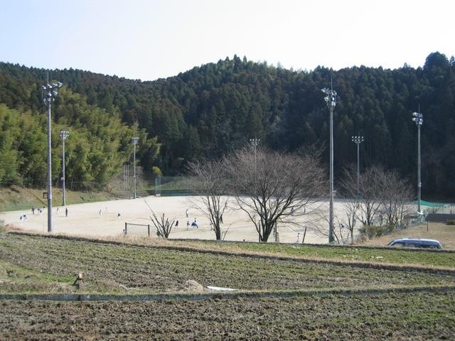 山あいの集落にある照明設備が整った土の三瀬グラウンドで、数人の人々がスポーツを楽しんでいる様子の写真